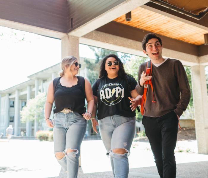 three students walking out of the career center smiling