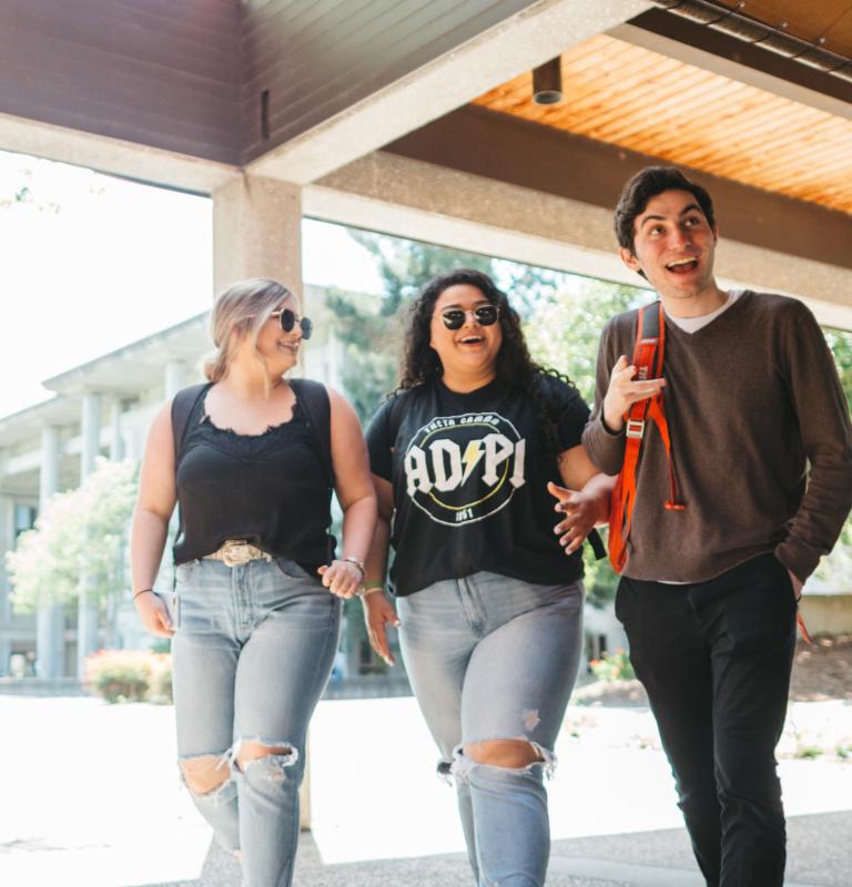 three students walking out of the career center smiling