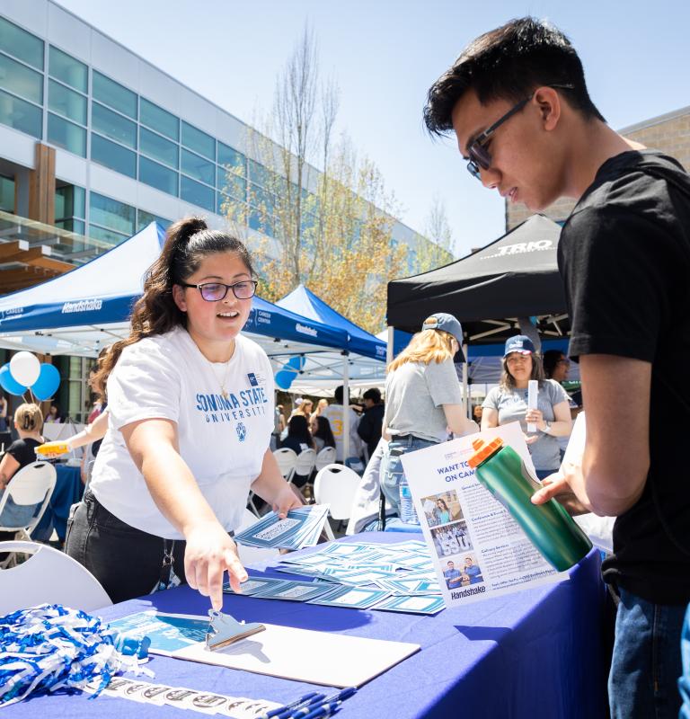 Staff member tabling and talking with a student