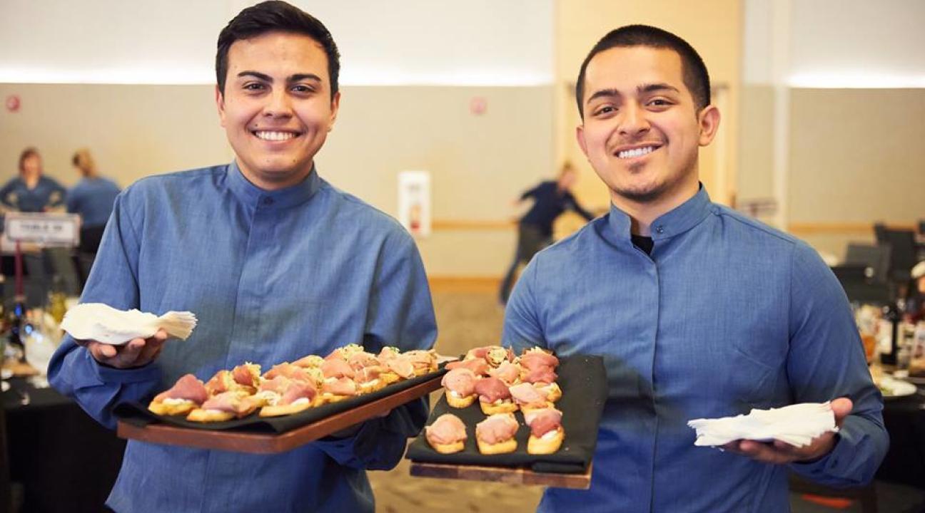 two students smiling and holding trays