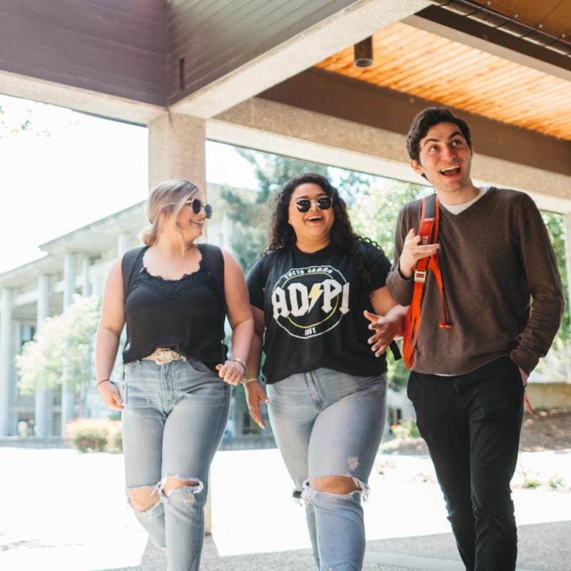 three students walking out of the career center smiling