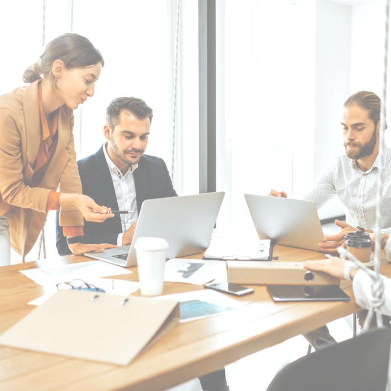 people sitting at a table with laptops working