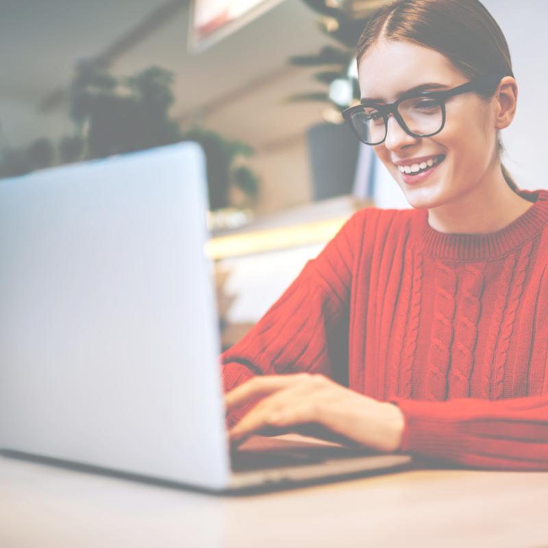 female professional wearing a red sweater and glasses working on a computer