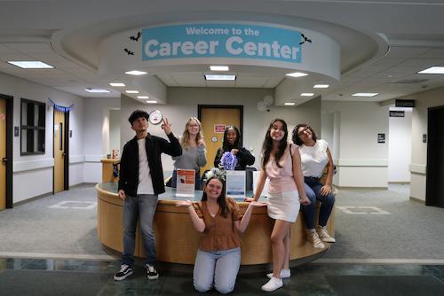 a group of students at the career center front desk smiling