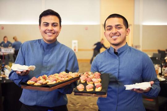 two students smiling and holding trays