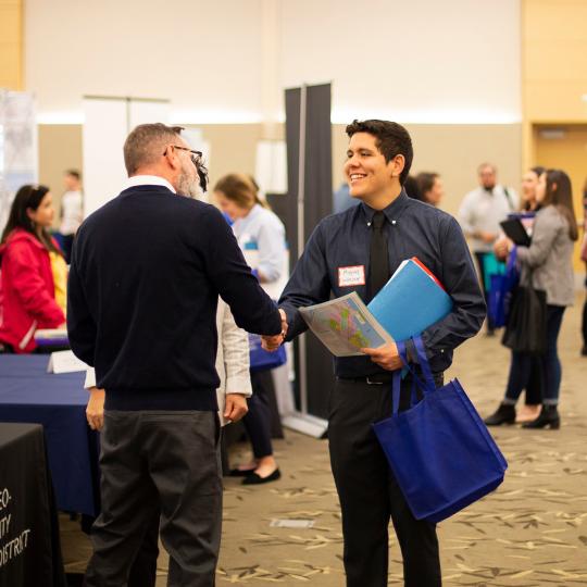 student speaking with potential employer at career fest table