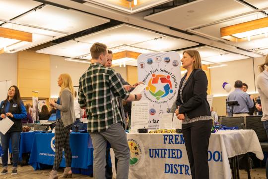 students talking to prospective employers at an indoor event