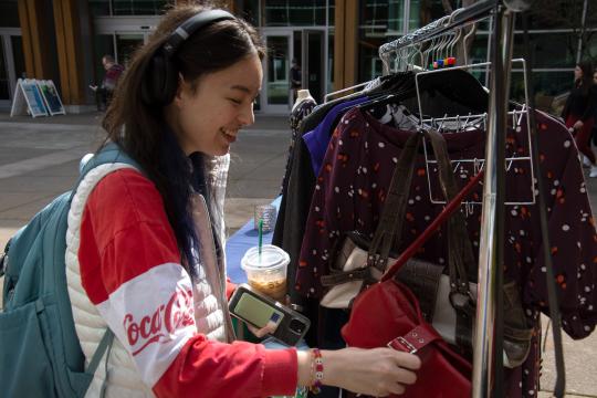 student looking through closes in career closet and smiling