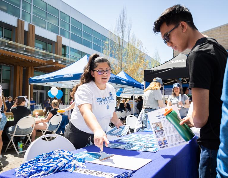 Staff member tabling and talking with a student
