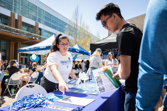 Staff member tabling and talking with a student